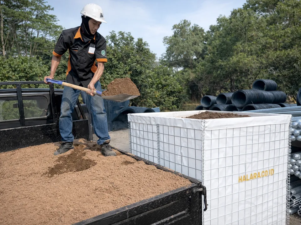 Petugas mengisi Bronjong Pasir Las Halarag berlapis geotextile putih dengan pasir